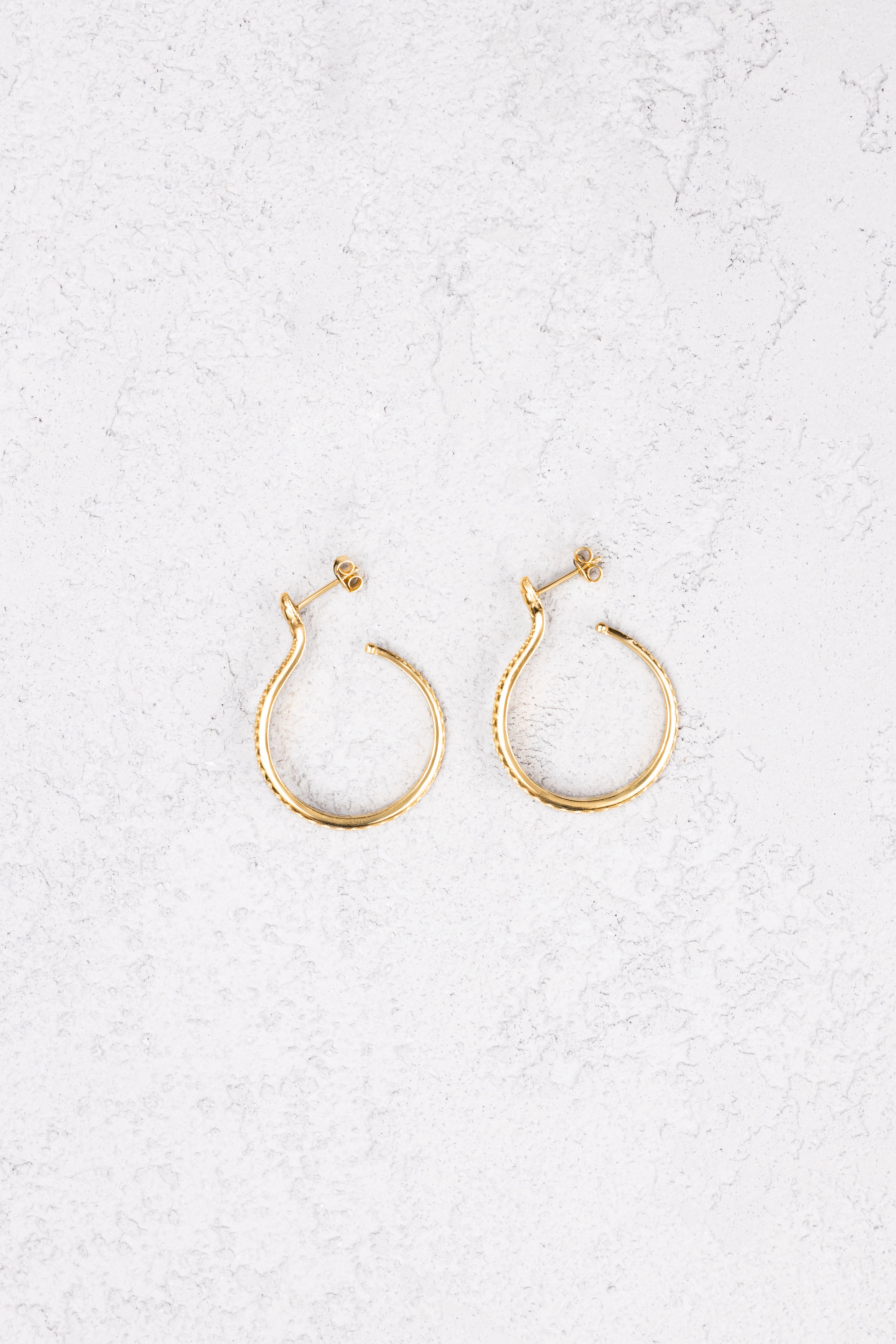 Sarpe serpent hoop earrings worn on bare skin, front view